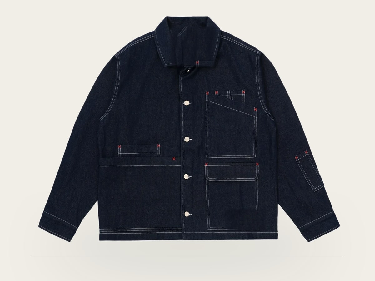 Indigo denim work jacket photographed flat, showing the placket, chest and hip pockets and contrast topstitching