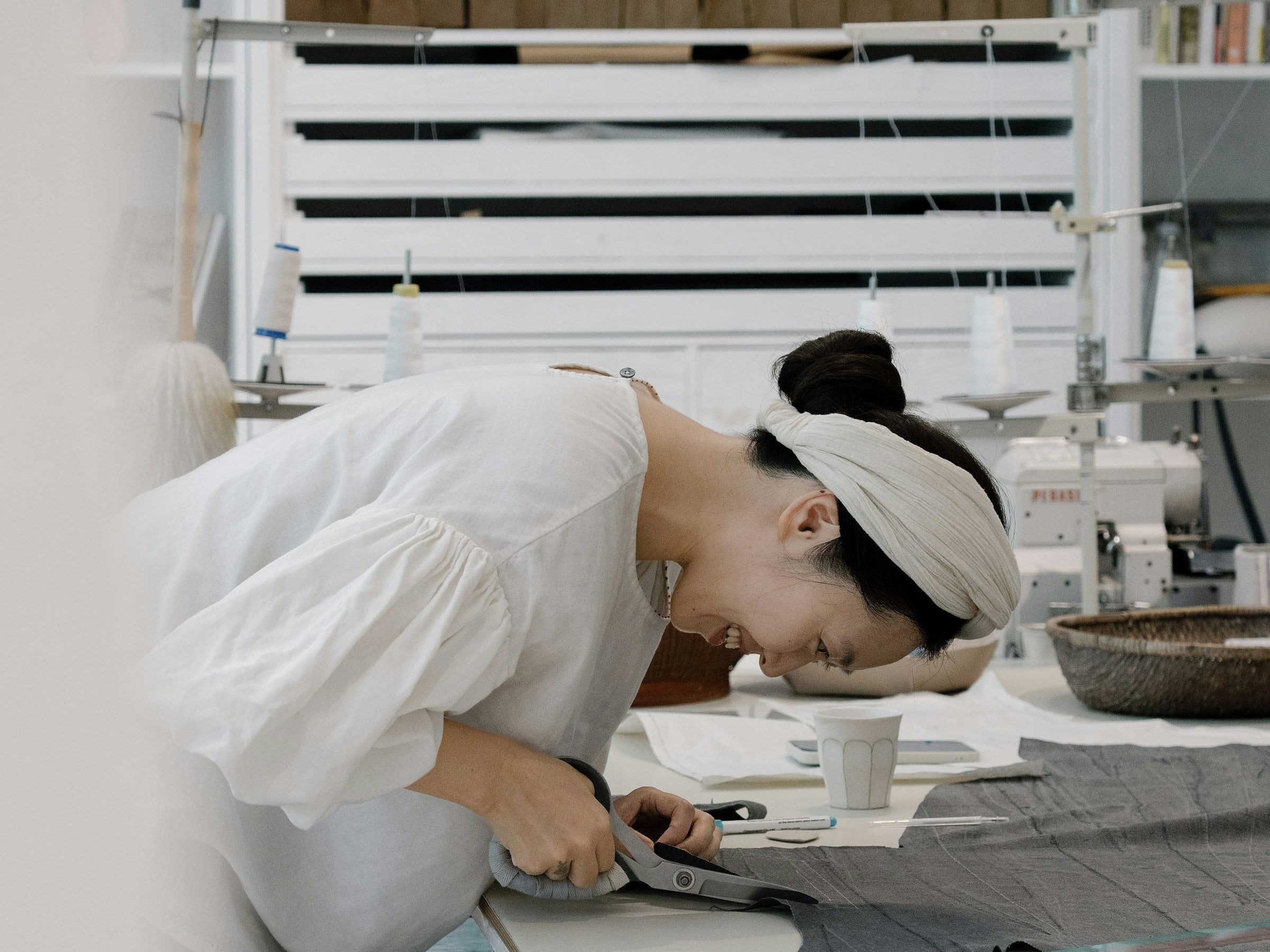 Pattern cutter working with grey fabric at a cutting table