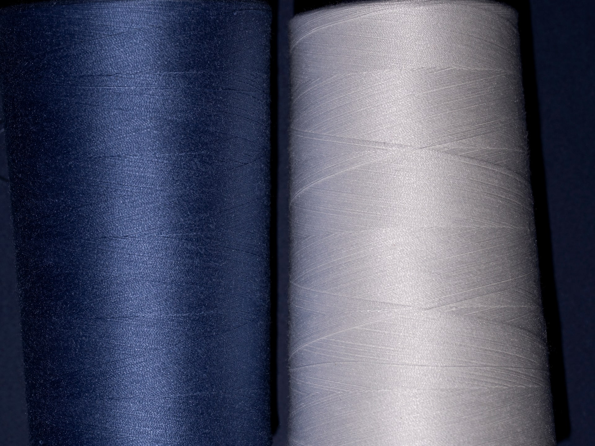 Two large yarn cones side by side, one navy and one cream