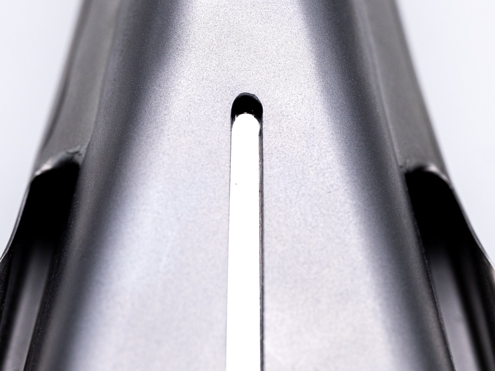 Macro detail of a metal machine housing with a single white cable running through it