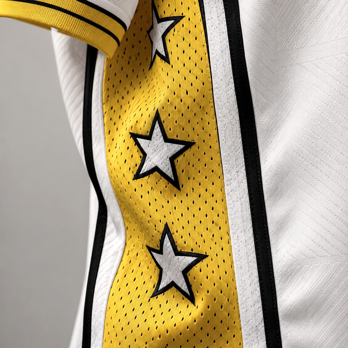 Close-up of a jersey side panel showing perforated mesh, rib, piping and applied star details