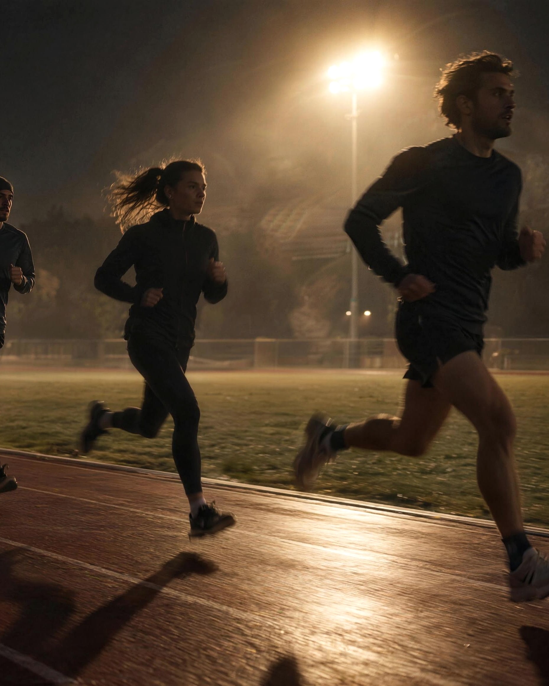 Runners training on a wet track under floodlights