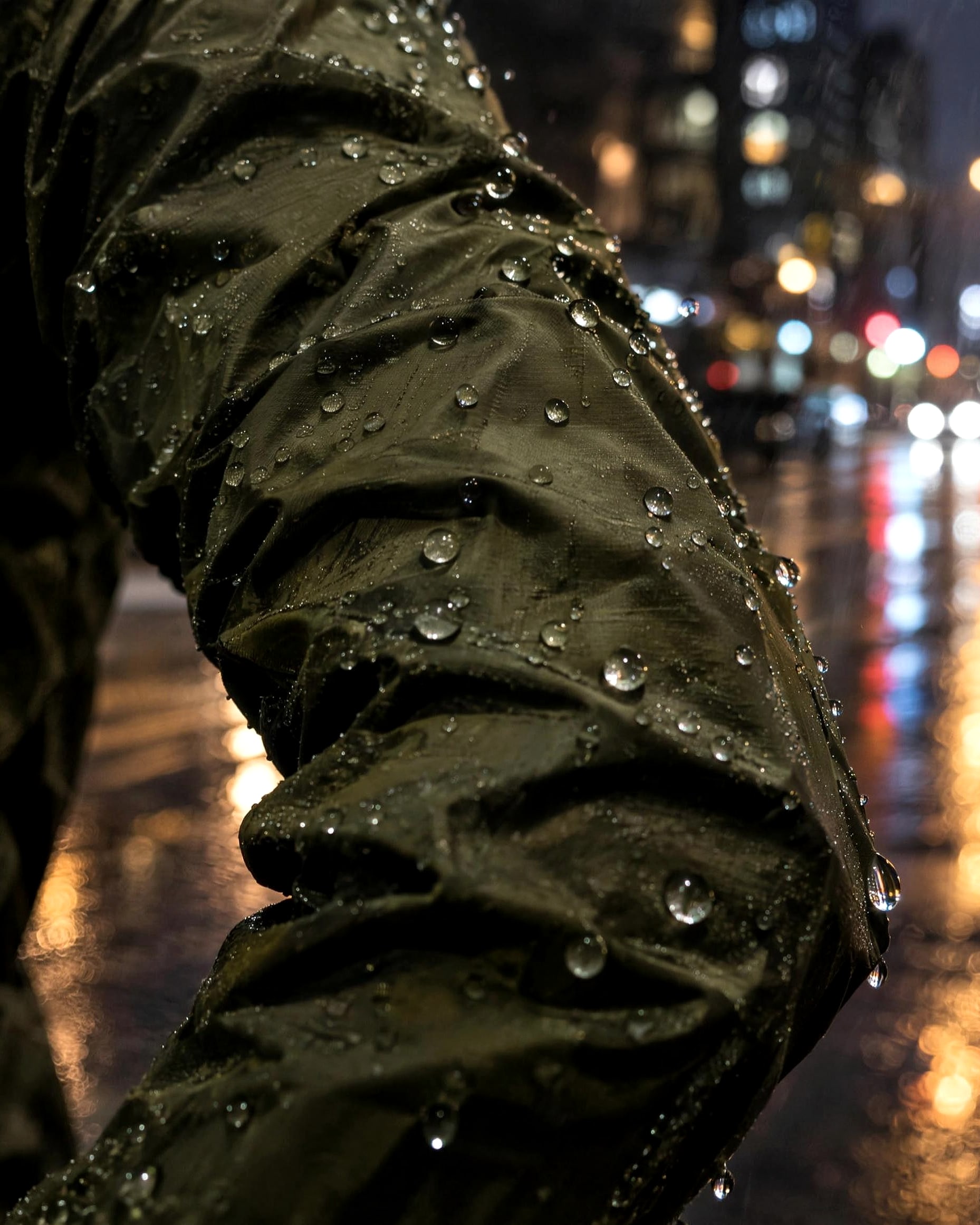 Water droplets beading on the sleeve of a dark running shell